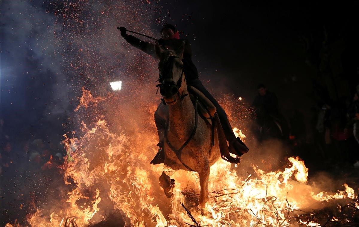 Una mujer monta un caballo a través de las llamas durante la celebración anual de Luminarias, la santa patrona de los animales en el pueblo de San Bartolomé de Pinares, al noroeste de Madrid.