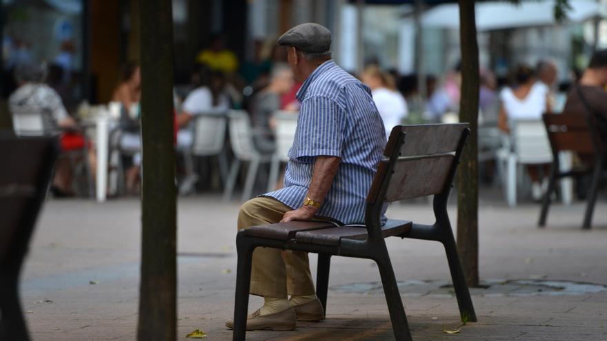 Un hombre mayor contempla desde un banco la actividad en una plaza en Pontevedra.