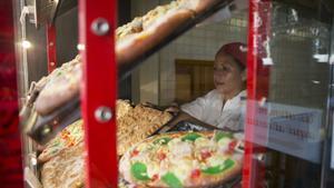 Una trabajadora coloca las cocas de Sant Joan en el escaparate del Forn Mistral de Barcelona.