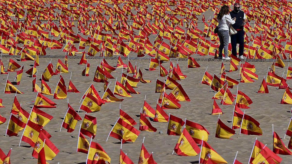 Dos personas, ayer, entre miles de banderas en la playa de la Patacona, en Valencia.