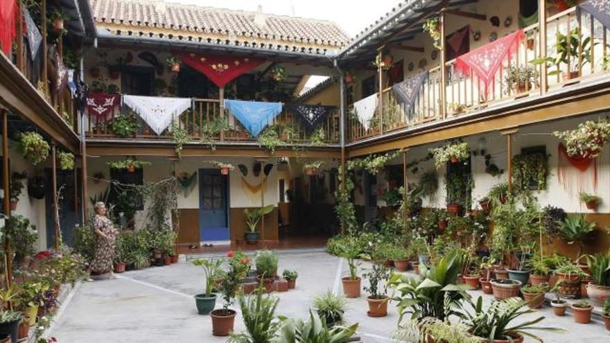 Corralón de la calle Feijóo, 6, con balcones de madera, mantones pintados a mano y numerosas plantas.