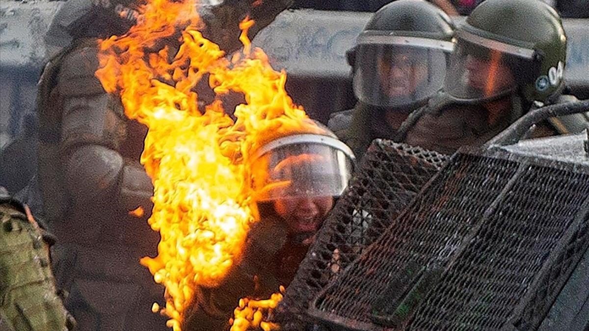 Una bomba de gasolina alcanza a los agentes de la policía antidisturbios durante los enfrentamientos con manifestantes que protestan contra las políticas económicas del gobierno del presidente Sebastián Piñera, en Santiago, el