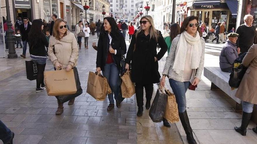 Clientas con bolsas de compras por la calle Larios.