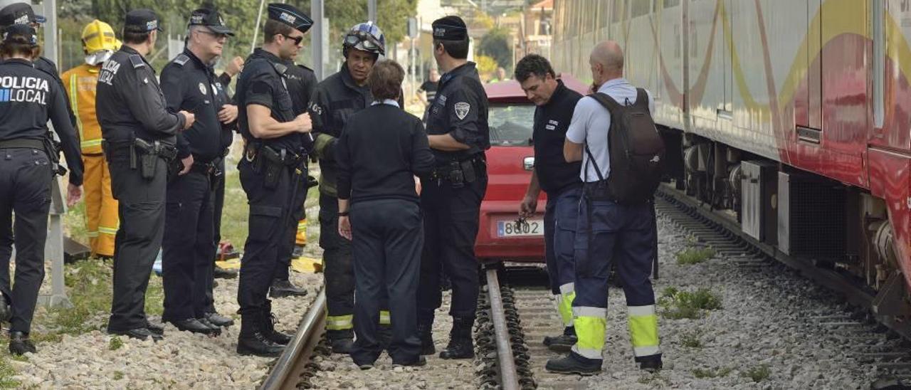 Bomberos y policías, junto al coche que fue arrollado por un tren el jueves a mediodía en un paso a nivel de Palma.