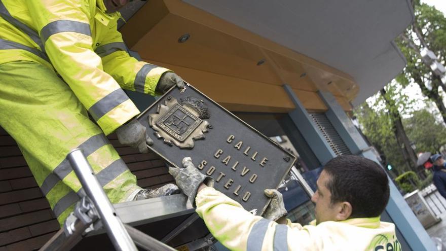 Dos operarios retiran una placa de la calle Calvo Sotelo, en abril de 2018