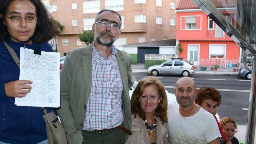 Un grupo de vecinos afectados con un escrito con firmas y el edificio Pintos al fondo. // G.Núñez