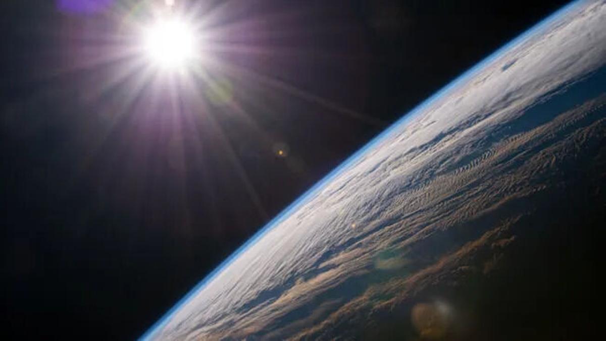 El sol brillante sobre la curva del borde de la tierra, con la delgadez de la atmósfera aparente