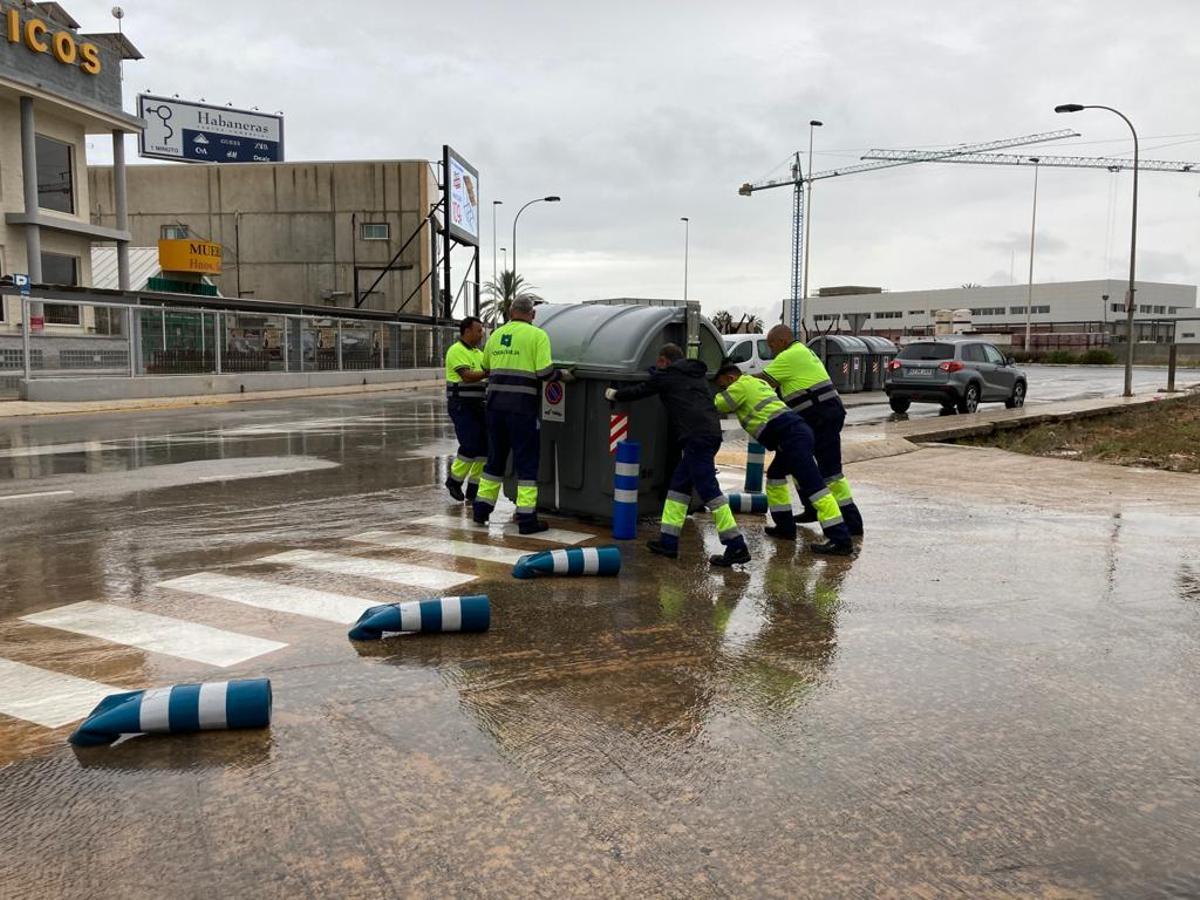 Operarios de Acciona recuperan los contenedores arrastrados por el agua en la avenida de Joaquín García junto a la CV-905