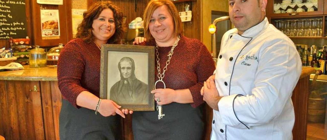 Por la izquierda, Manolita y Elisa Piloñeta sujetan el retrato de su bisabuela La Pacha junto a su hermano Óscar.