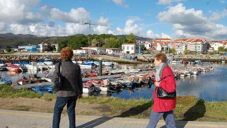 Dos mujeres pasean ante los pantalanes del muelle de Arcade. // FdV