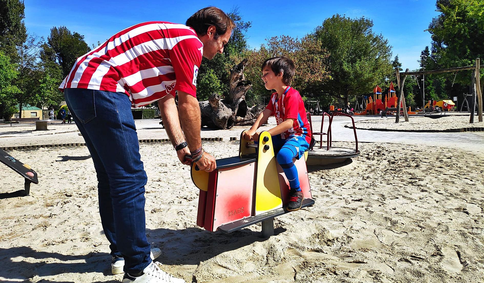 Juan Suárez ayuda a su hijo Sergio en un balancín de la zona de juegos de Isabel la Católica.