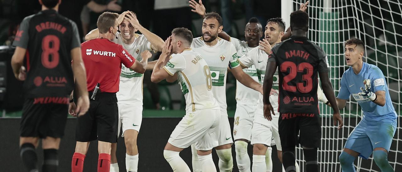 Los jugadores del Elche piden explicaciones al colegiado del encuentro tras la pena máxima señalada a Badía sobre Raíllo.