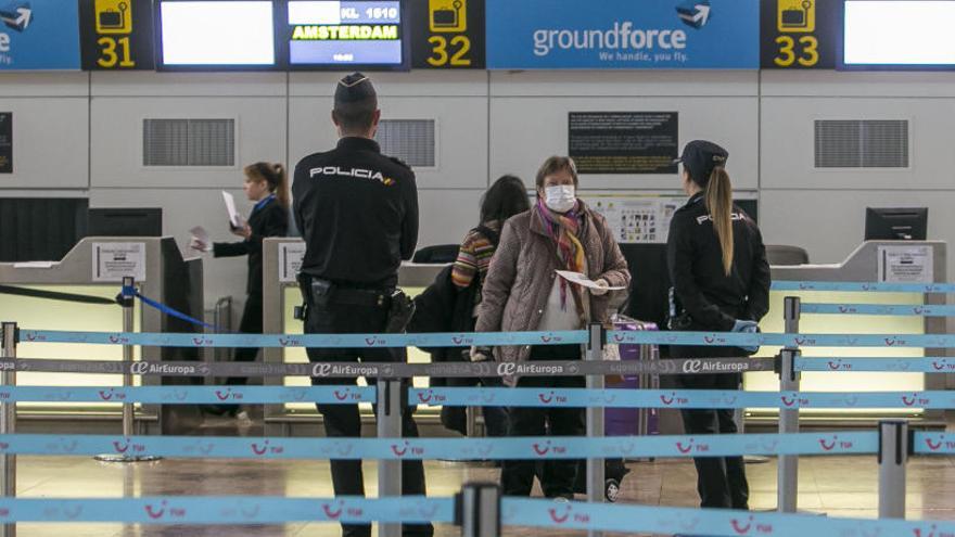 Dos policías nacionales vigilan la facturación de uno de los últimos vuelos, ayer, en el aeropuerto.