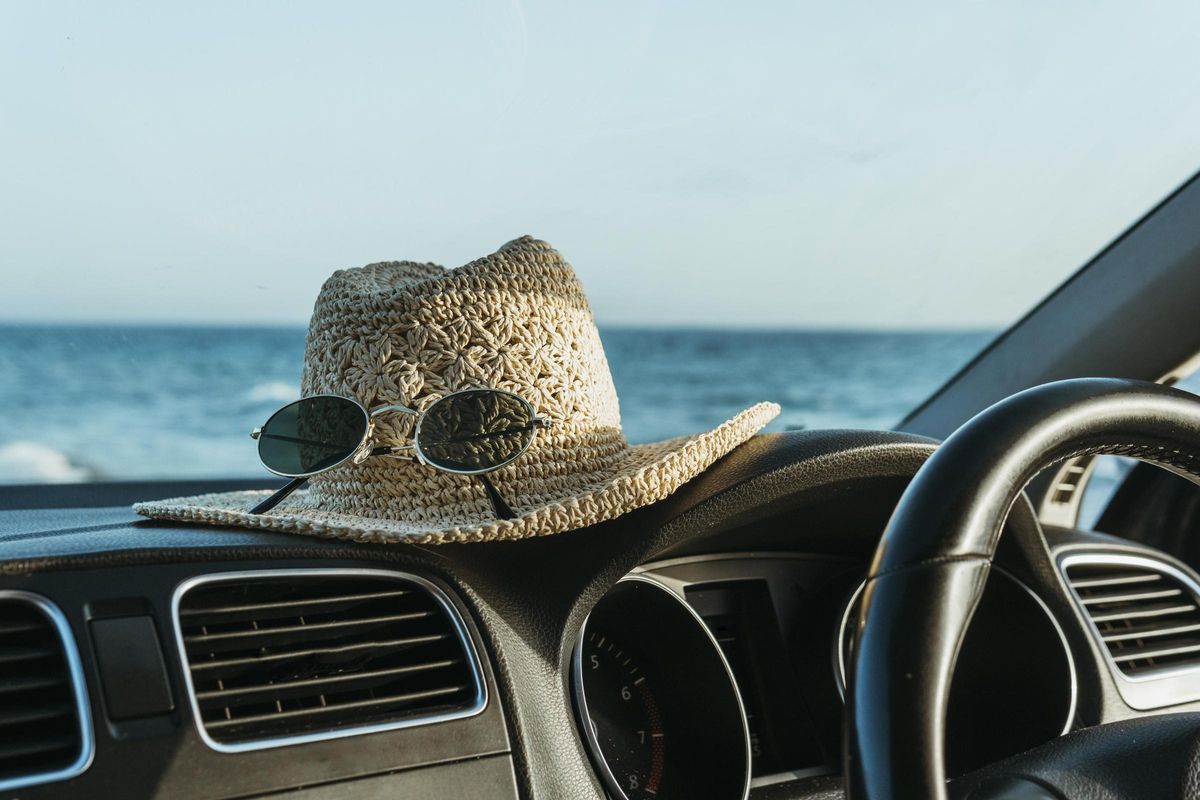 Un sombrero y gafas de sol en un coche al lado de la playa