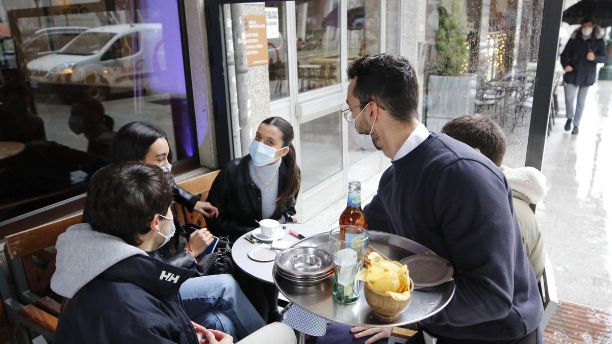 Un camarero sirviendo a los clientes en la terraza de una cafetería de Vigo. Alba Villar