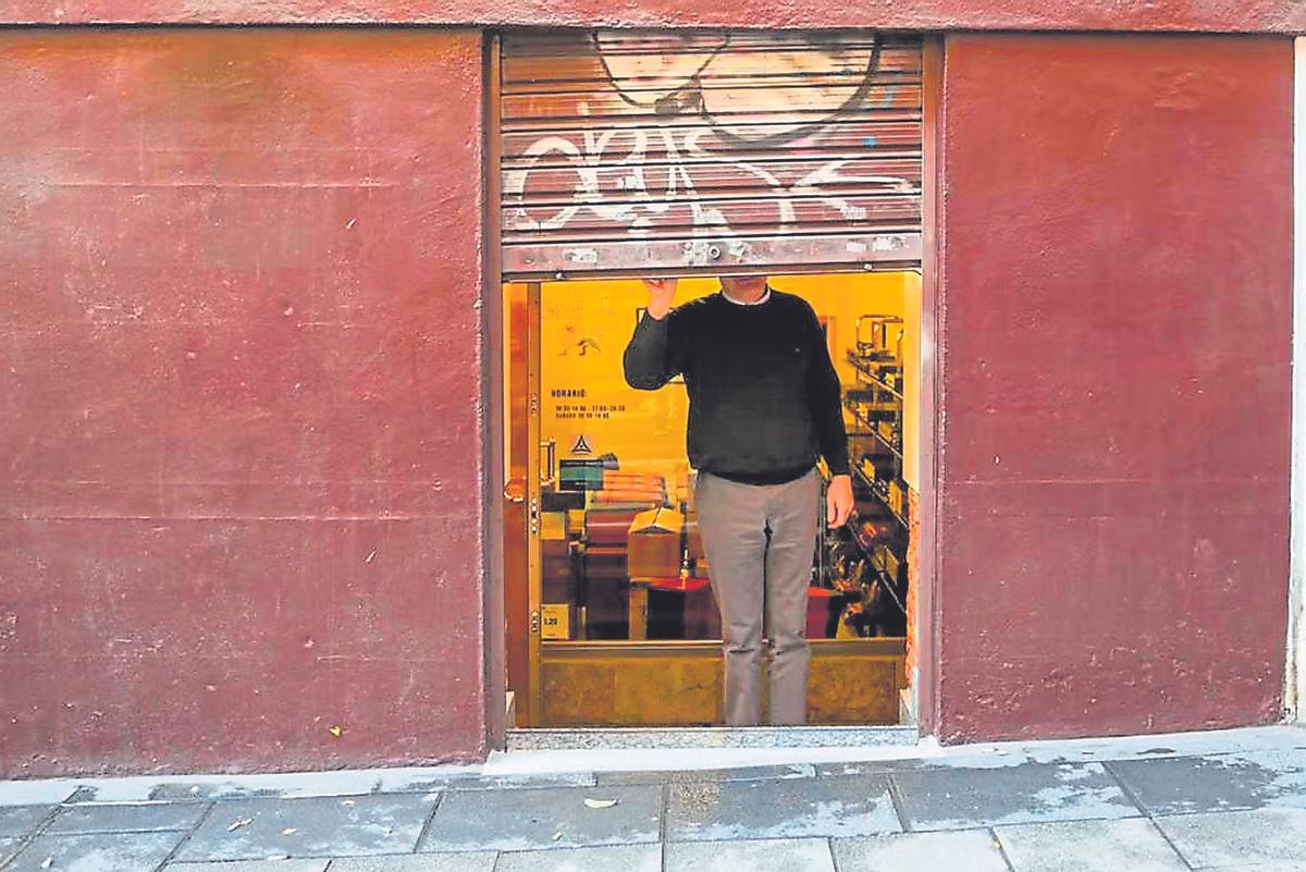 Un autónomo cerrando la persiana de su negocio al terminar su jornada laboral.