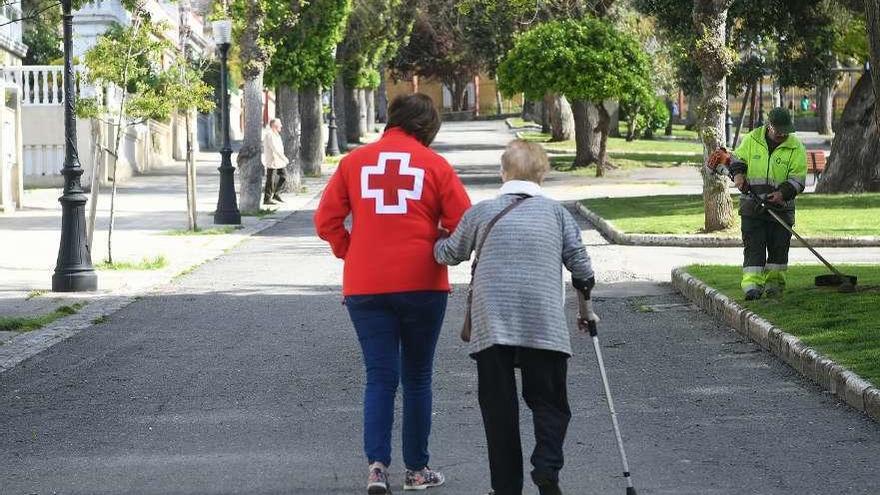 Una voluntaria de Cruz Roja pasea con una mujer mayor.