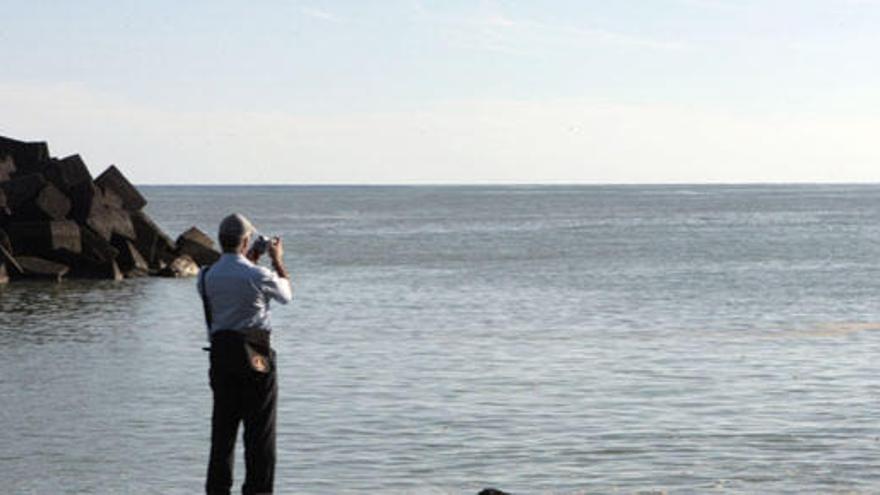 Un hombre fotografía la mancha en el puerto de La Restinga. i EFE