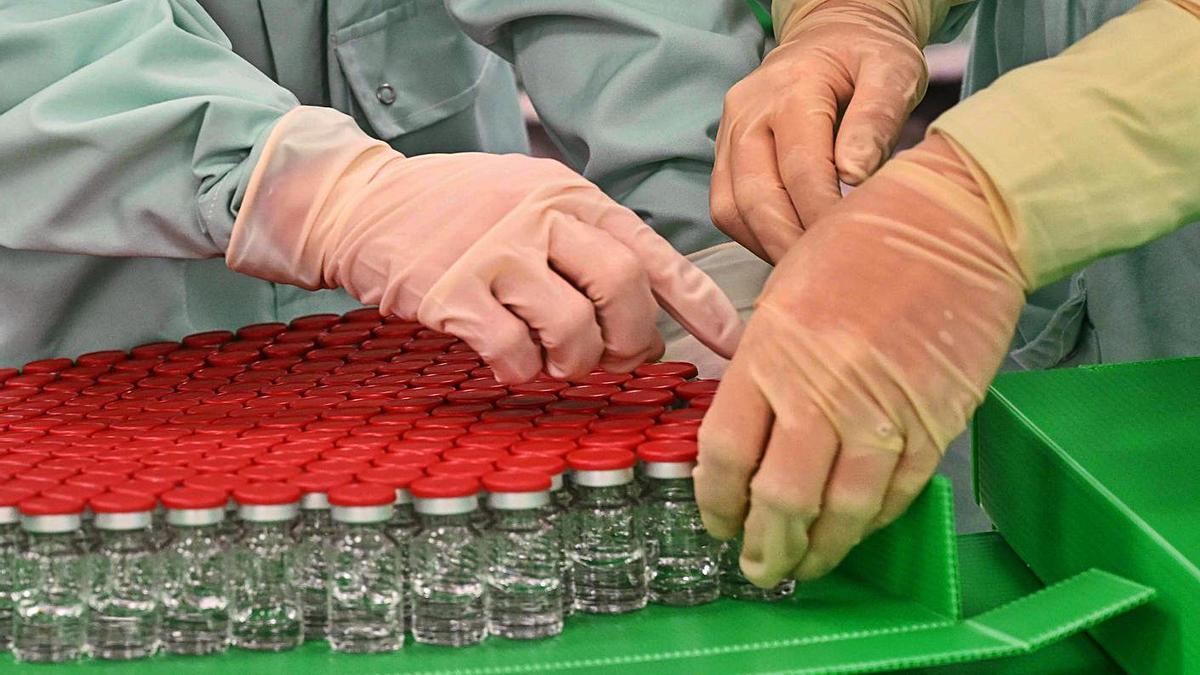 Dos técnicos preparan viales de la vacuna de AstraZeneca, en Oxford. |  // AFP