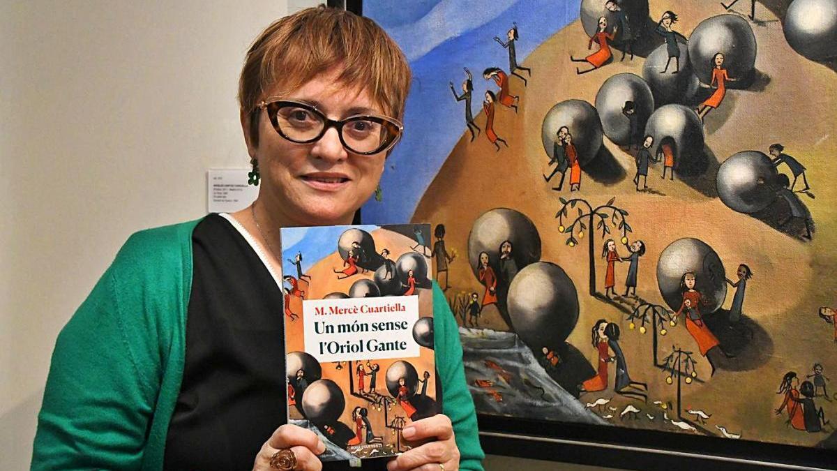 M. Mercè Cuartiella fotografiada amb el nou llibre davant l&#039;obra &#039;La Terra&#039;, d&#039;Ángeles Santos