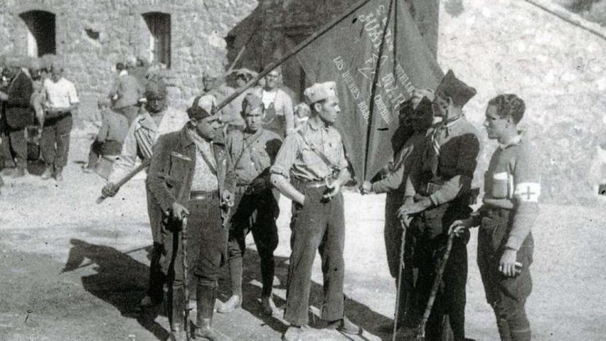 La guerra en el frente inmortalizada por el doctor Manuel Usano. Fotografía tomada en el frente de Teruel. Aparecen los mandos del batallón Juan Marco con su bandera, en la que se lee el lema «los duendes rojos». El primero por la derecha es Manuel Usano Martín, capitán médico del batallón.