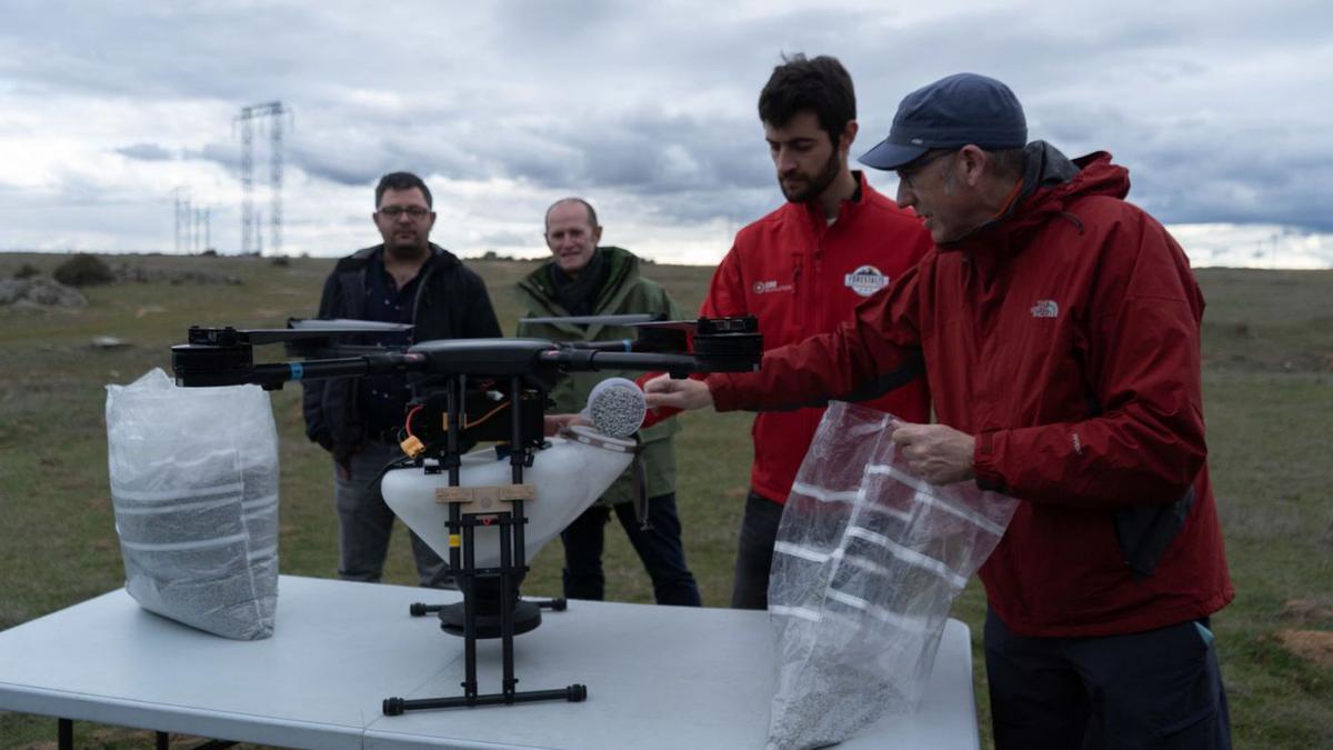 Los operadores de CO2 Revolution cargan el dron de semillas. Al fondo, Luis A. Miguel  y Miguel Calvo. | J. L. Fdez.