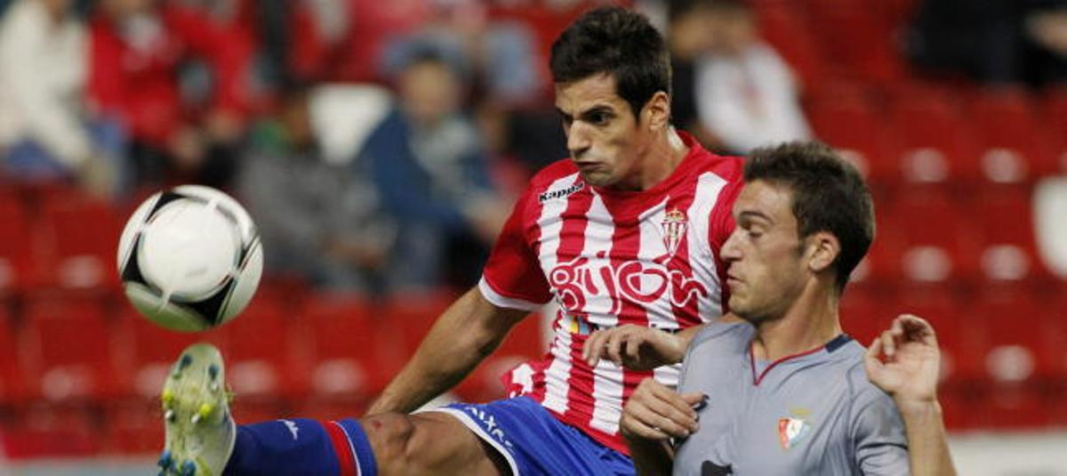 El defensa del Sporting de Gijon Pedro Orfila (i), pelea un balón com el delantero de Osasuna Roberto Torres.