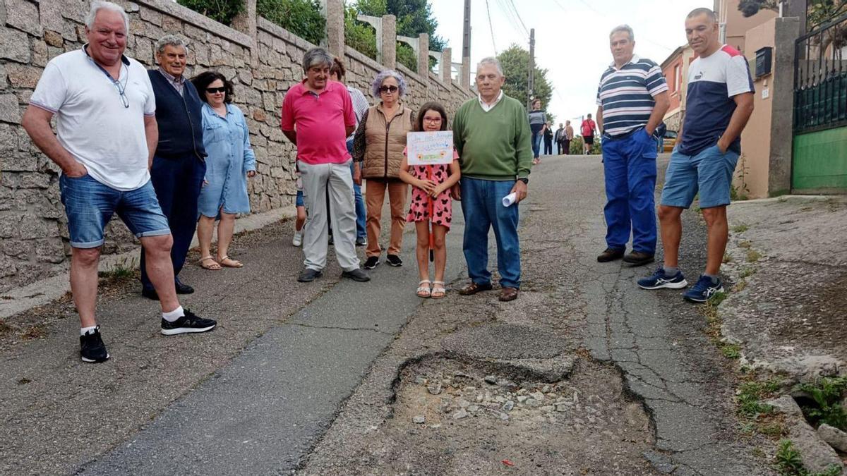 Los vecinos protestan junto a uno de los baches en el inicio del Camiño do Couto de Reboreda, ayer.