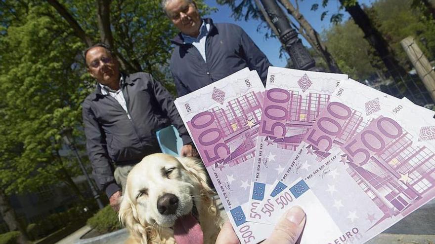 Dos personas observan cómo su perro &#039;olfatea&#039; unas réplicas de billetes de 500 euros.