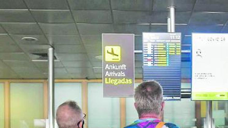 Dos turistas británicos miran el panel de vuelos del aeropuerto. | | ANDRÉS CRUZ