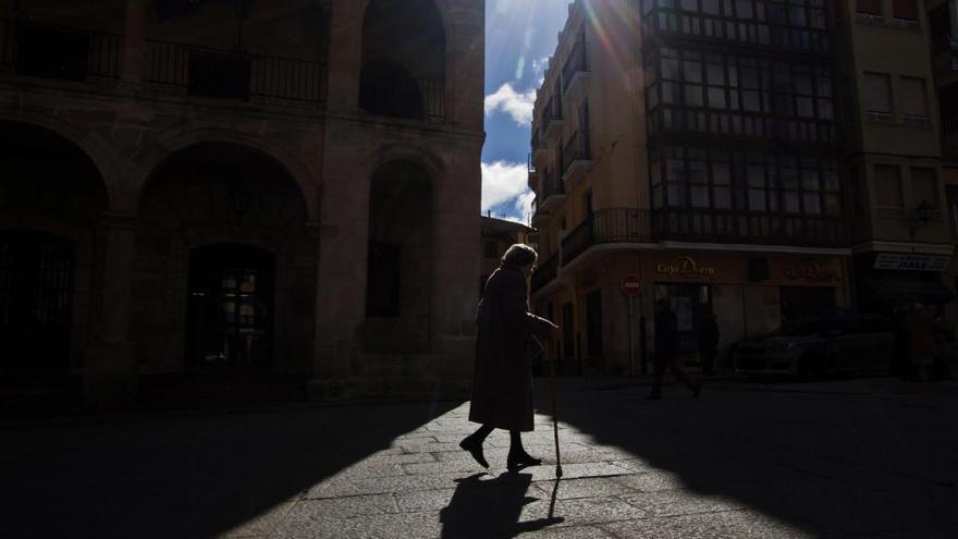 Una anciana camina por la Plaza Mayor.