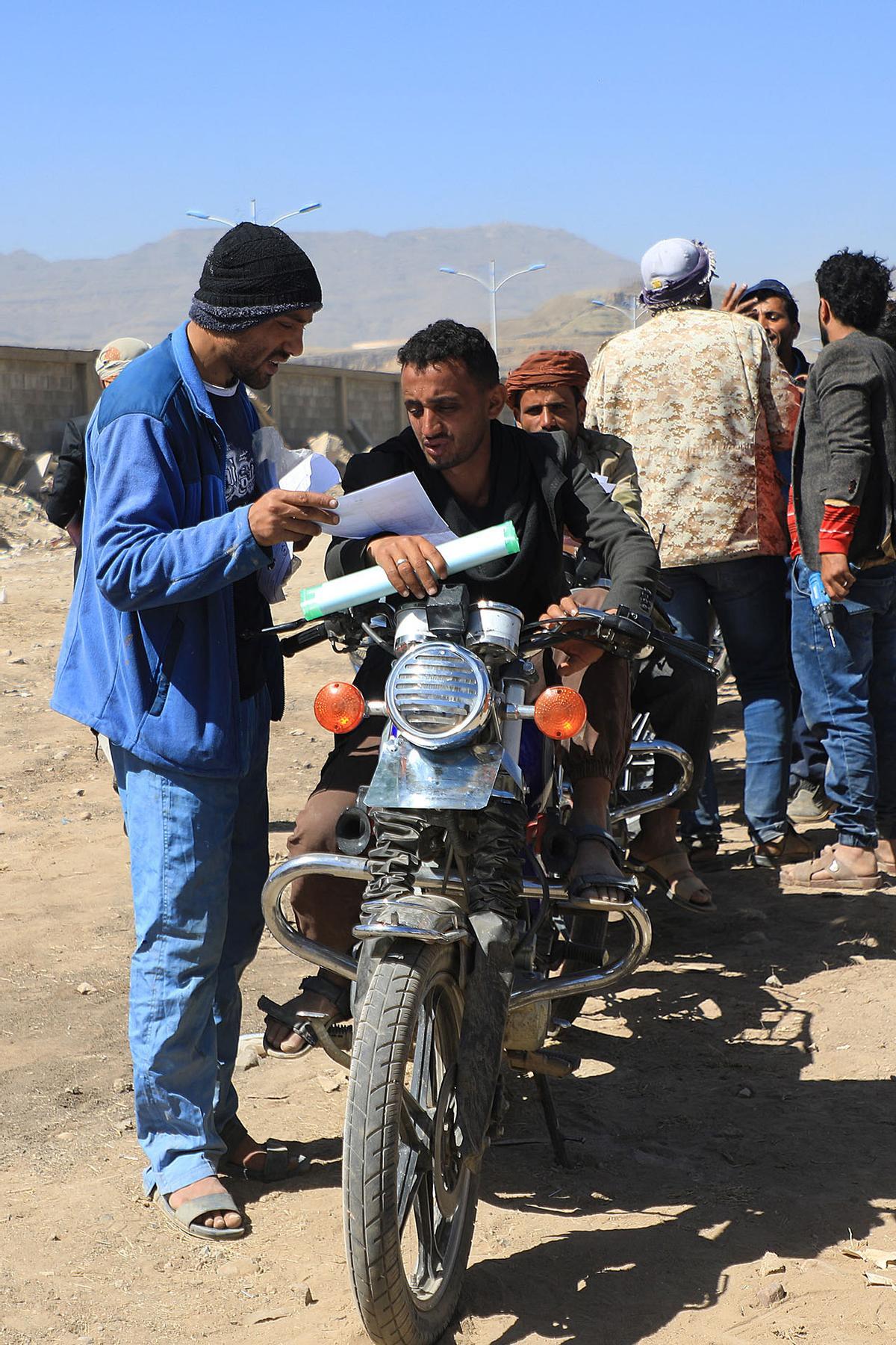 Los yemeníes se reúnen en medio de motocicletas mientras esperan que se les expidan licencias para conducir como parte de una campaña de seguridad de las autoridades huzíes, en Yemen