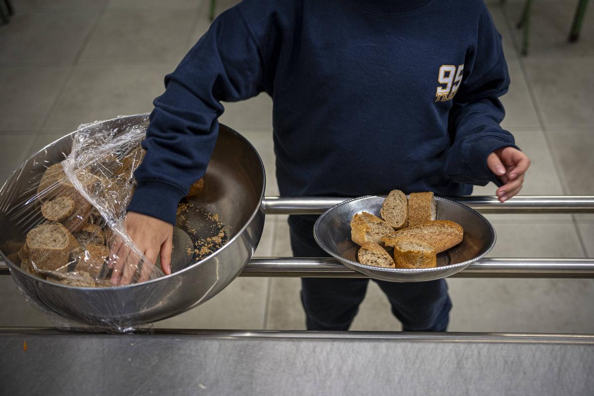 Un alumno prepara el pan integral para su mesa en el comedor de la escuela.