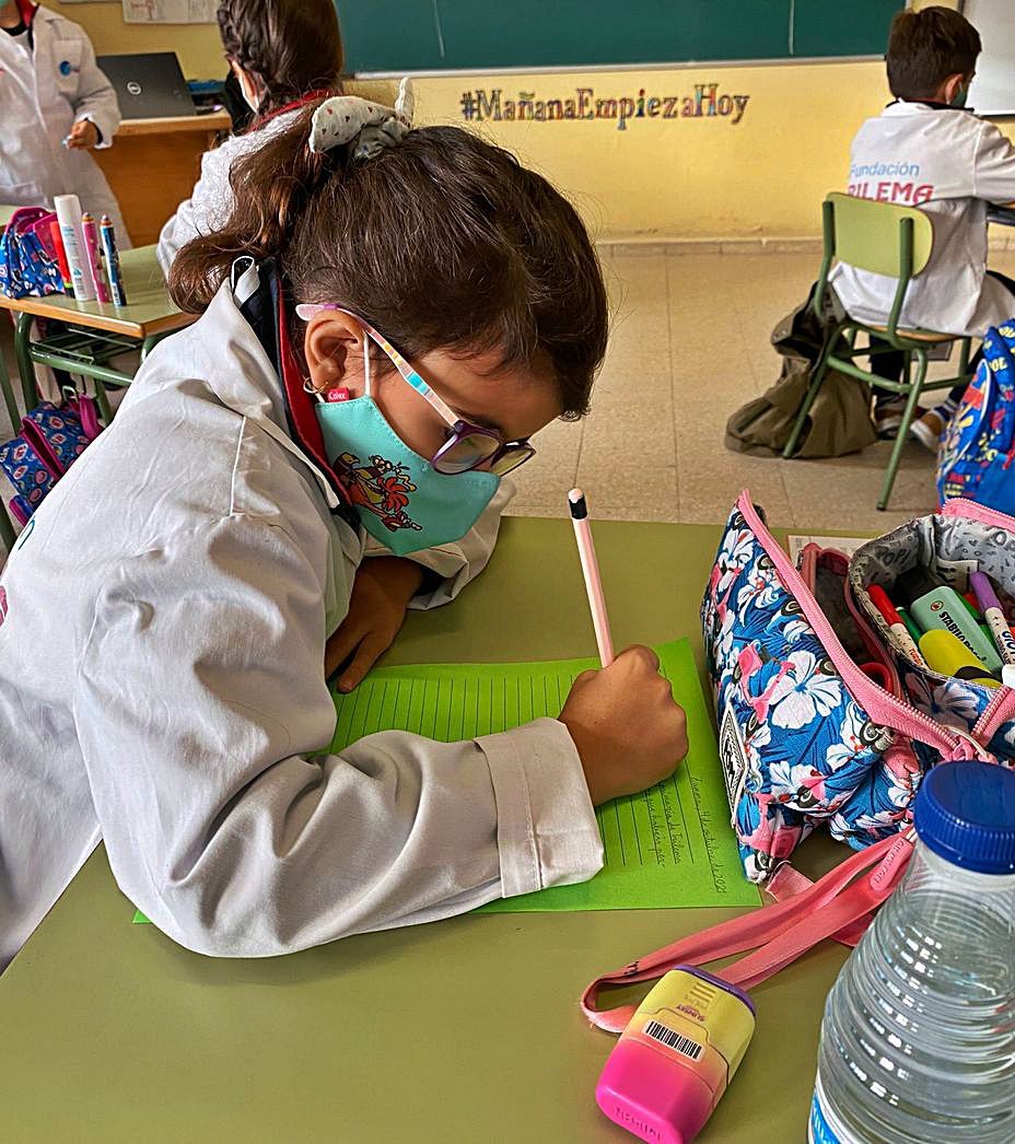 Una alumna escribe en papel de color.