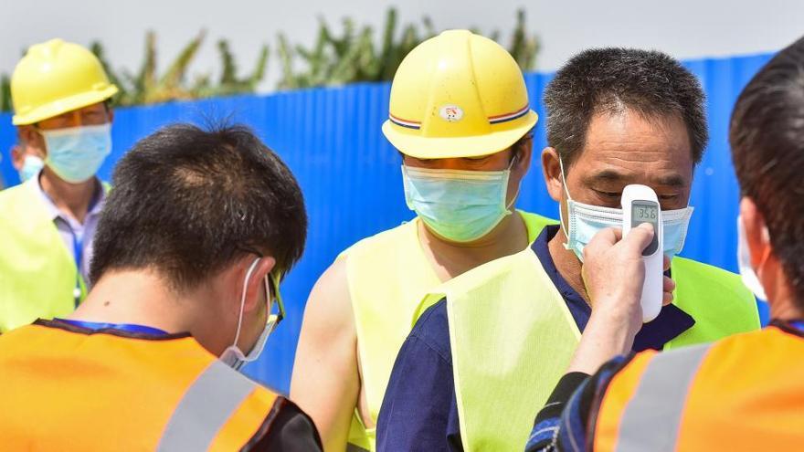 Trabajadores se toman la temperatura en China.