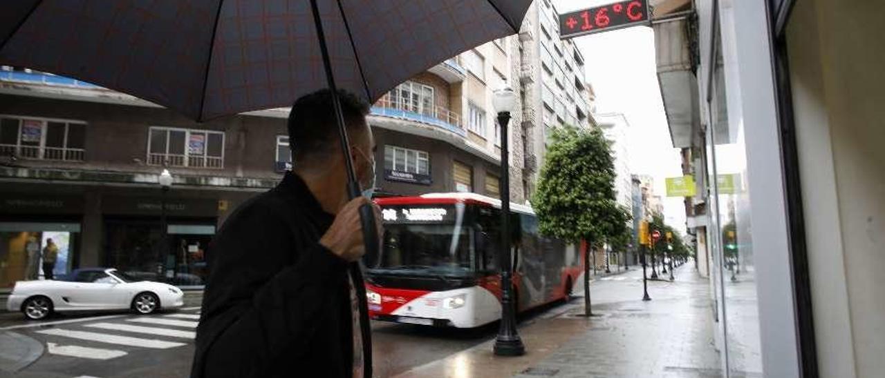 Un peatón con mascarilla ve pasar un autobús de Emtusa en la calle Menéndez Valdés.