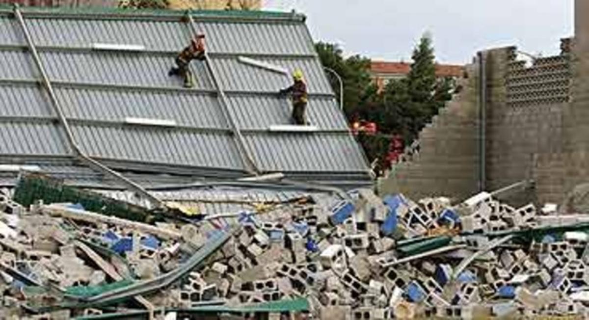 Unos bomberos inspeccionan el techo del polideportivo del Sant Boi.