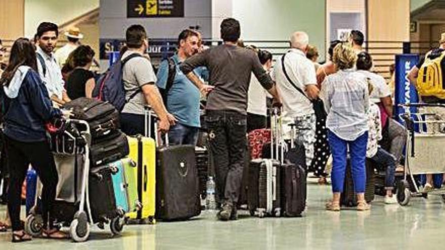 Pasajeros guardando cola frente al mostrador de facturación en Ibiza.