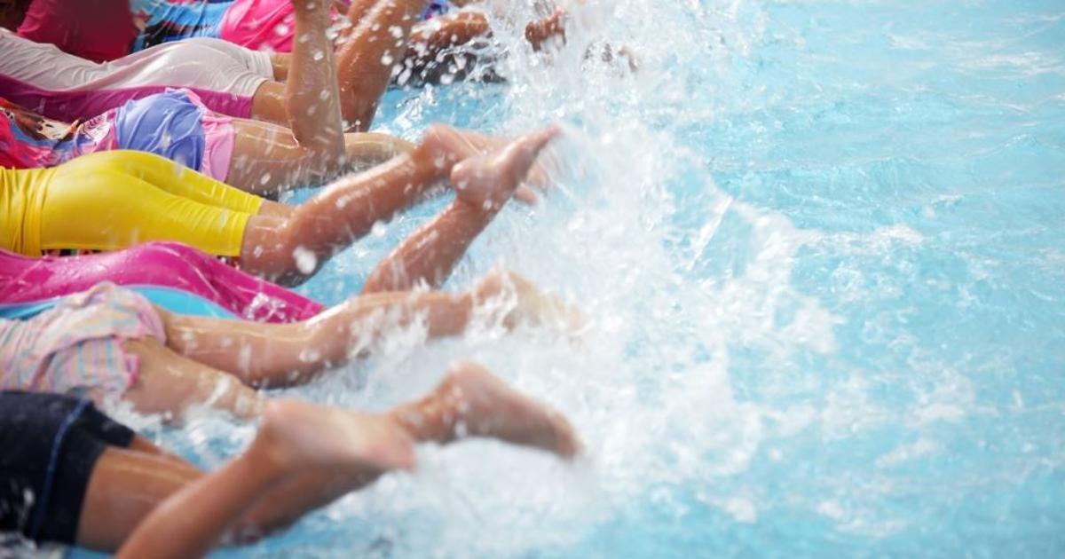 Un grupo de pequeños dando la patadas de crol en la piscina.