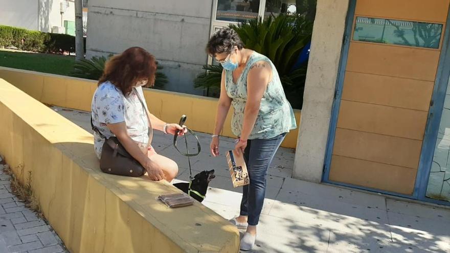 Encarna García entrega comida para animales a la dueña de un perro, ayer en el Centro de Servicios Sociales del Distrito de Churriana.