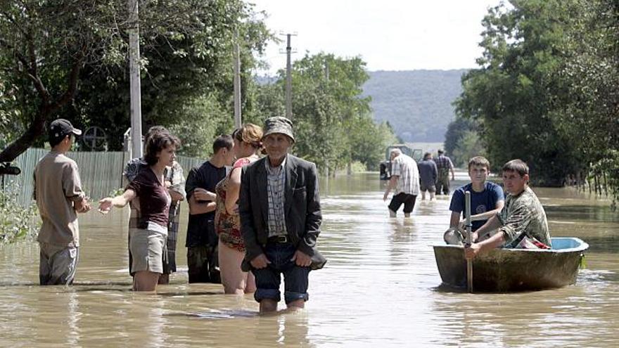 Varias personas avanzan, a pie o en barca a remos, por una calle inundada del pueblo de Poberezhya, en la región de Ivano-Frankivsk (Ucrania), el 28 de julio de 2008.