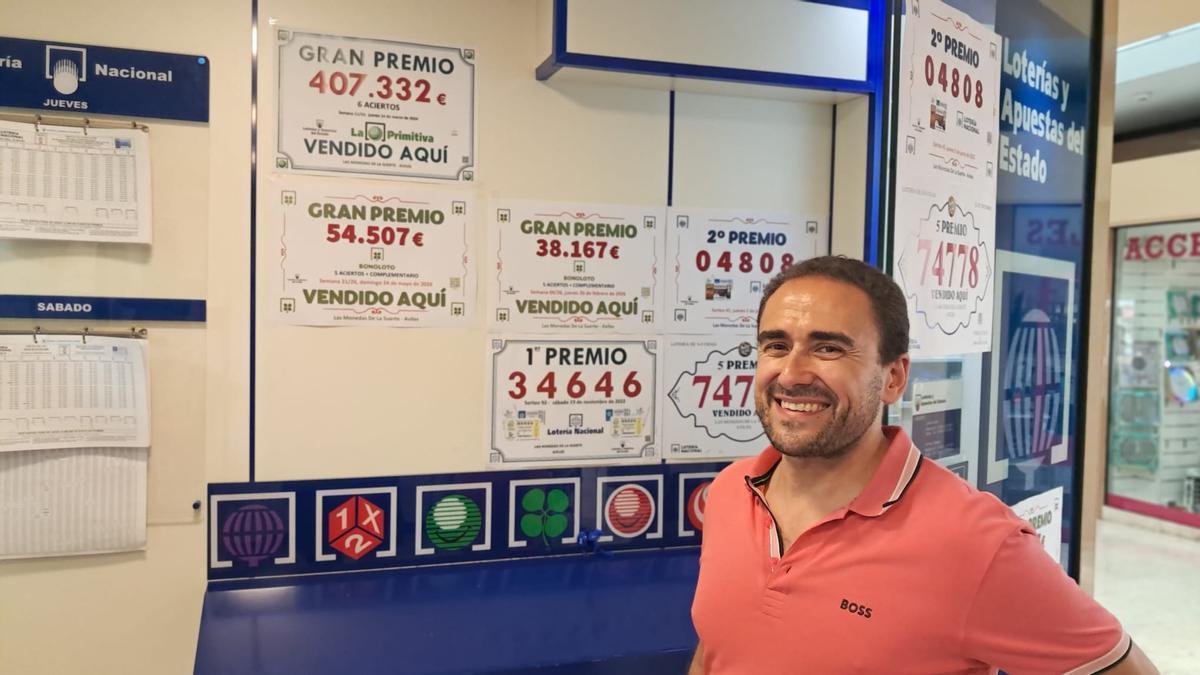 José Arias, titular de la admnistración, posa en el muro en el que coloca los carteles de los premios entregados.