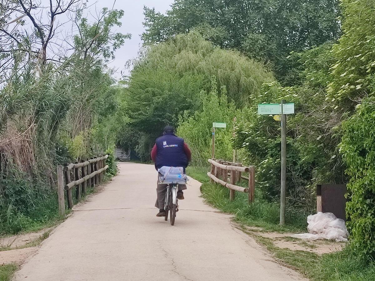 Un home transporta tres garrafes amb una bicicleta.