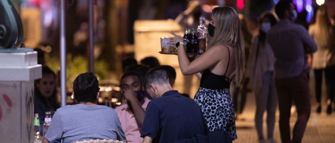 Una camarera atiende una mesa en una terraza.