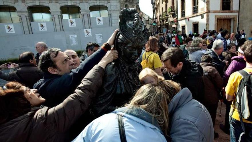 Un grupo de invidentes, ayer, tocando la estatua de la Regenta en la plaza de la Catedral. | miki lópez
