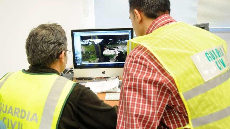 Dos agentes de la unidad de delitos telemáticos observan un mapa con localizaciones de redes wifi.