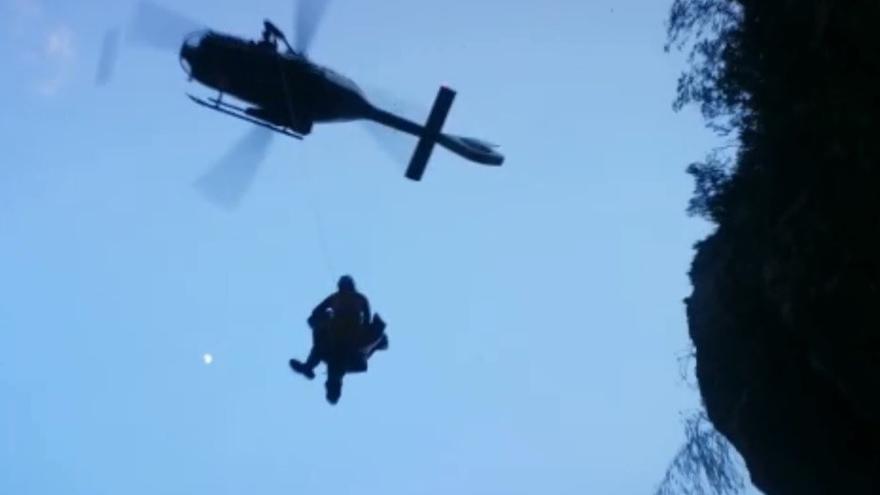 El helicóptero extrae del barranco al excursionista y al guardia civil que lo ha rescatado.