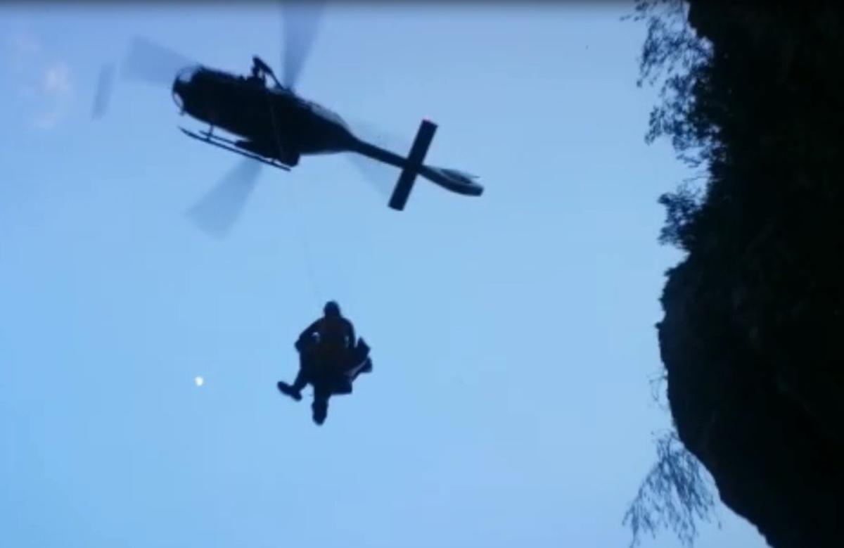 El helicóptero extrae del barranco al excursionista y al guardia civil que lo ha rescatado.