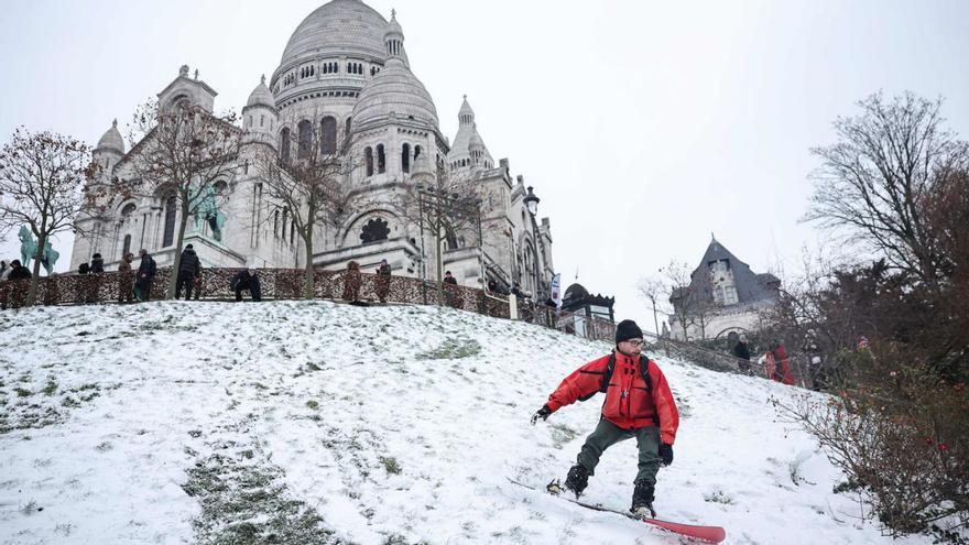 Un home amb una planxa de neu baixant als peus de la basílica del Sacré Coeur de Montmartre, a París, ahir. | ANNE-CHRISTINNE POUJOULAT / AFP