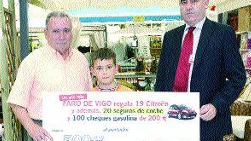 Manuel Táboas, con su nieto, recibe el seguro de manos de Antonio Lanero. / r. grobas